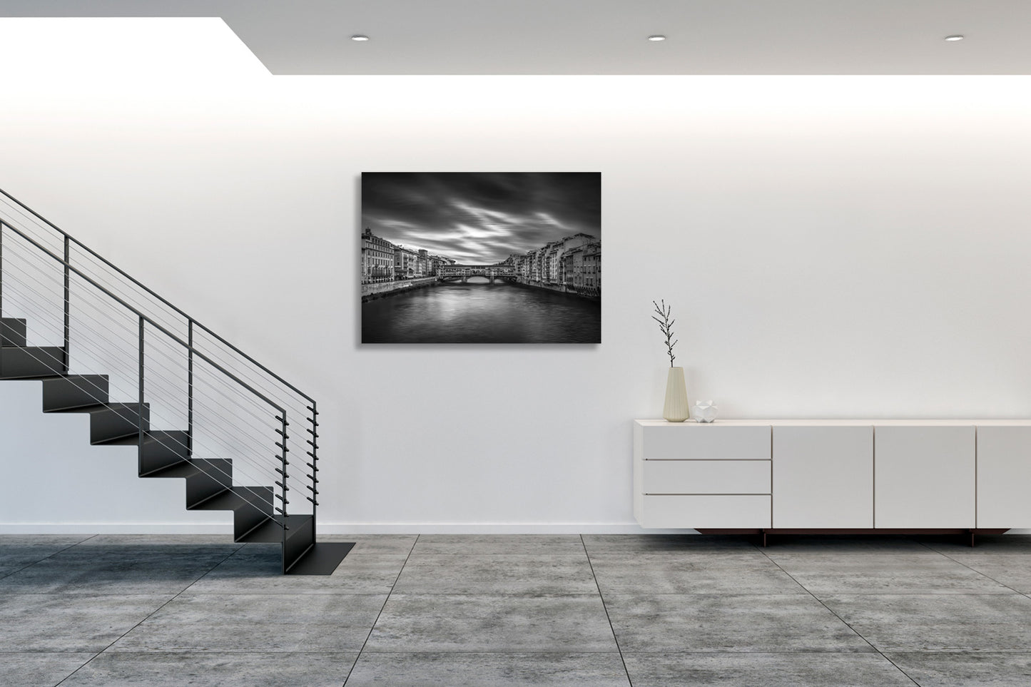 Fotografia fine art in bianco e nero incorniciata di Ponte Vecchio a Firenze, esposta in ambiente domestico moderno con arredamento minimalista.
Black and white fine art photograph shown framed of Ponte Vecchio in Florence, displayed in modern home interior with minimalist furnishings.