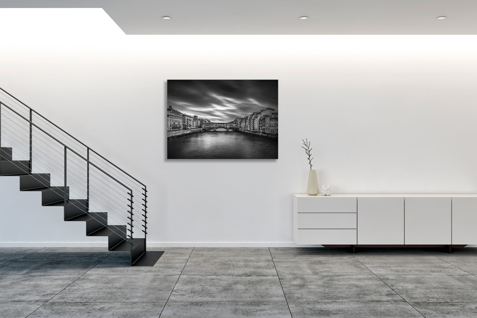 Fotografia fine art in bianco e nero incorniciata di Ponte Vecchio a Firenze, esposta in ambiente domestico moderno con arredamento minimalista.
Black and white fine art photograph shown framed of Ponte Vecchio in Florence, displayed in modern home interior with minimalist furnishings.