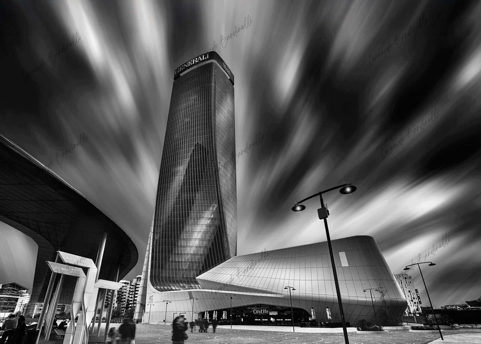 Fotografia fine art in bianco e nero di architettura contemporanea a Milano, con il grattacielo Generali ripreso dal basso e una lunga esposizione che crea un cielo dinamico e mosso.
Black and white fine art photograph of contemporary architecture in Milan, featuring the Generali tower shot from a low angle, with long exposure creating a dynamic, streaked sky.