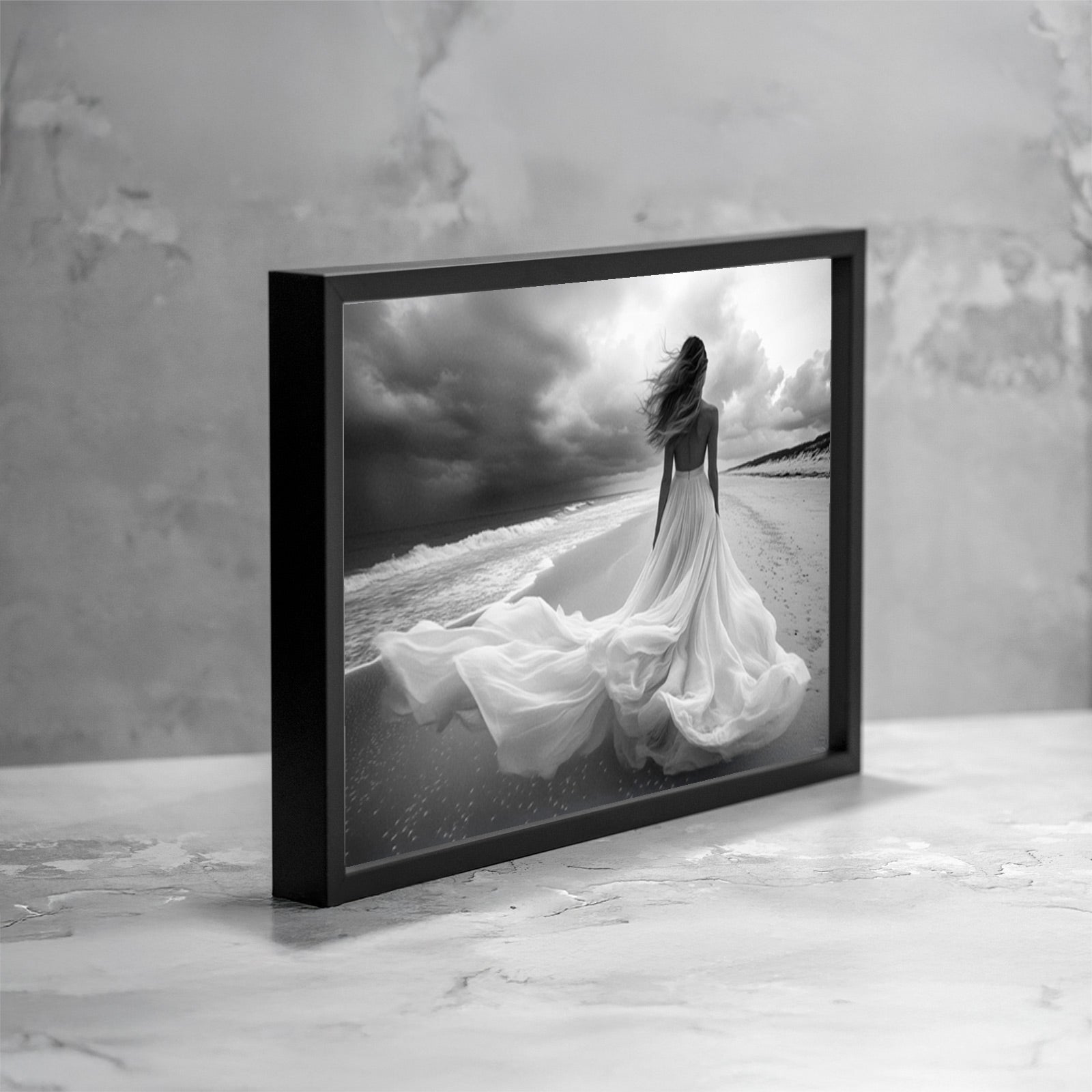 Fotografia fine art in bianco e nero incorniciata di una figura femminile di spalle sulla riva del mare, con un abito leggero mosso dal vento, le onde sulla battigia e un cielo tempestoso, presentata in una vista angolata come esempio di ambientazione.
Black and white fine art photograph shown framed of a female figure seen from behind on a seashore, wearing a flowing dress moved by the wind, with waves along the shoreline and a stormy sky, presented in an angled view as an example of display.
