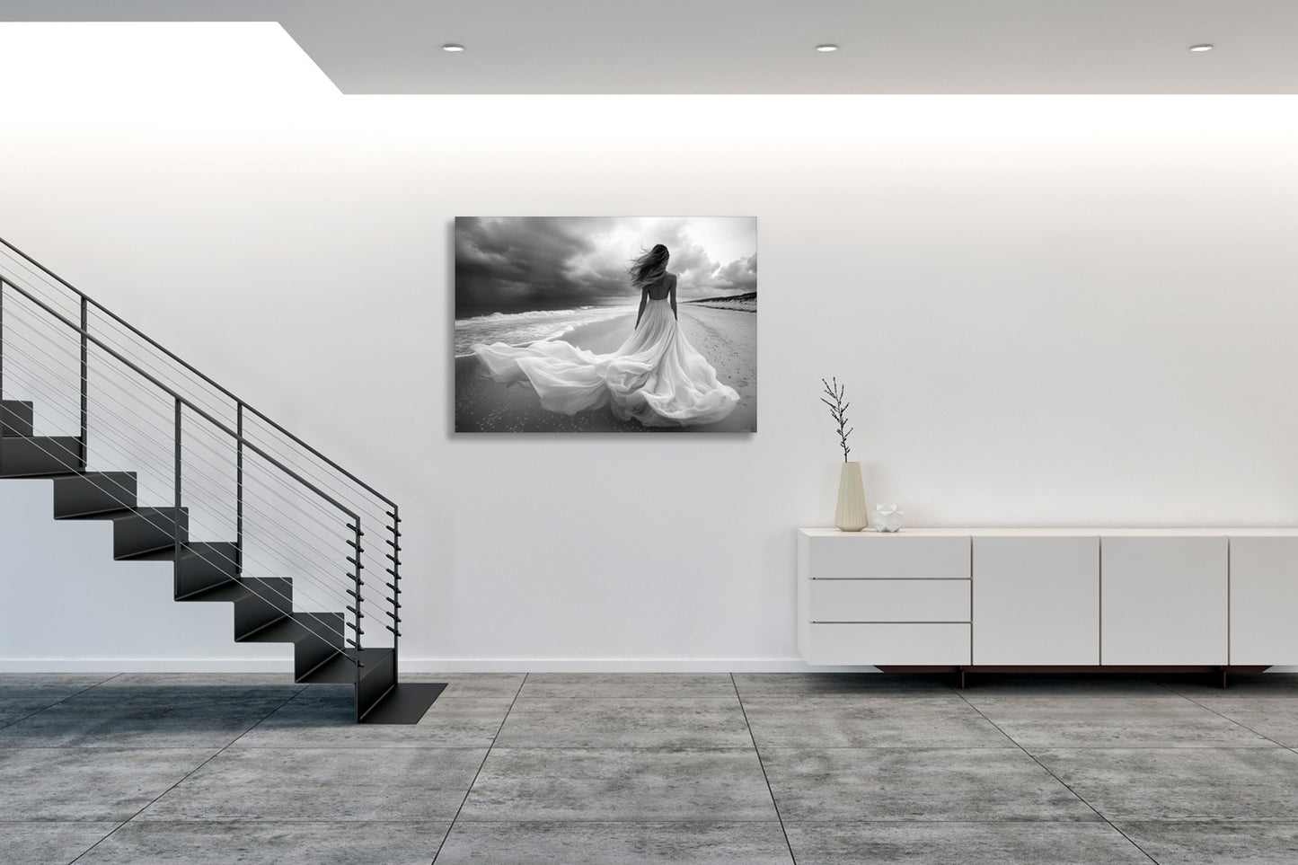 Fotografia fine art in bianco e nero incorniciata di figura femminile sulla riva del mare, esposta in un ambiente gallery minimale con parete bianca, presentata in una terza prospettiva per mostrare l'integrazione dell'opera nello spazio.
Black and white fine art photograph shown framed of a female figure on a seashore, displayed in a minimal gallery setting with white wall, presented in a third perspective to show the artwork's integration in the space.
