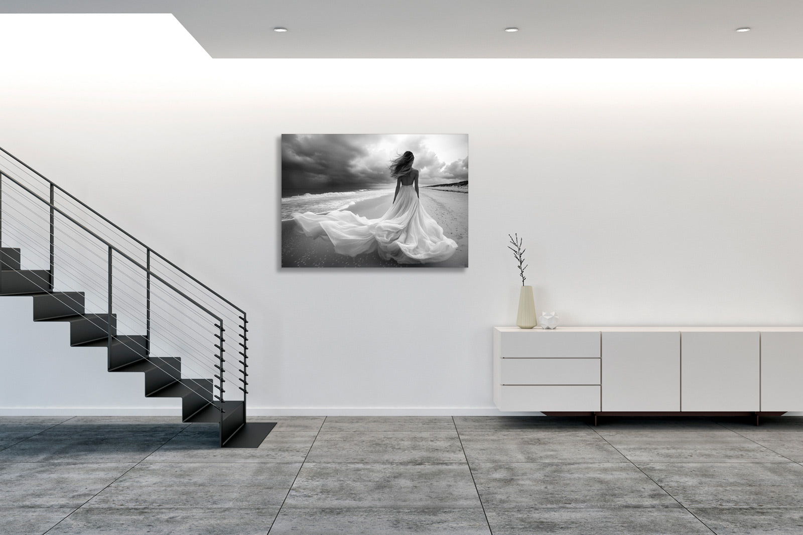 Fotografia fine art in bianco e nero incorniciata di figura femminile sulla riva del mare, esposta in un ambiente gallery minimale con parete bianca, presentata in una terza prospettiva per mostrare l'integrazione dell'opera nello spazio.
Black and white fine art photograph shown framed of a female figure on a seashore, displayed in a minimal gallery setting with white wall, presented in a third perspective to show the artwork's integration in the space.